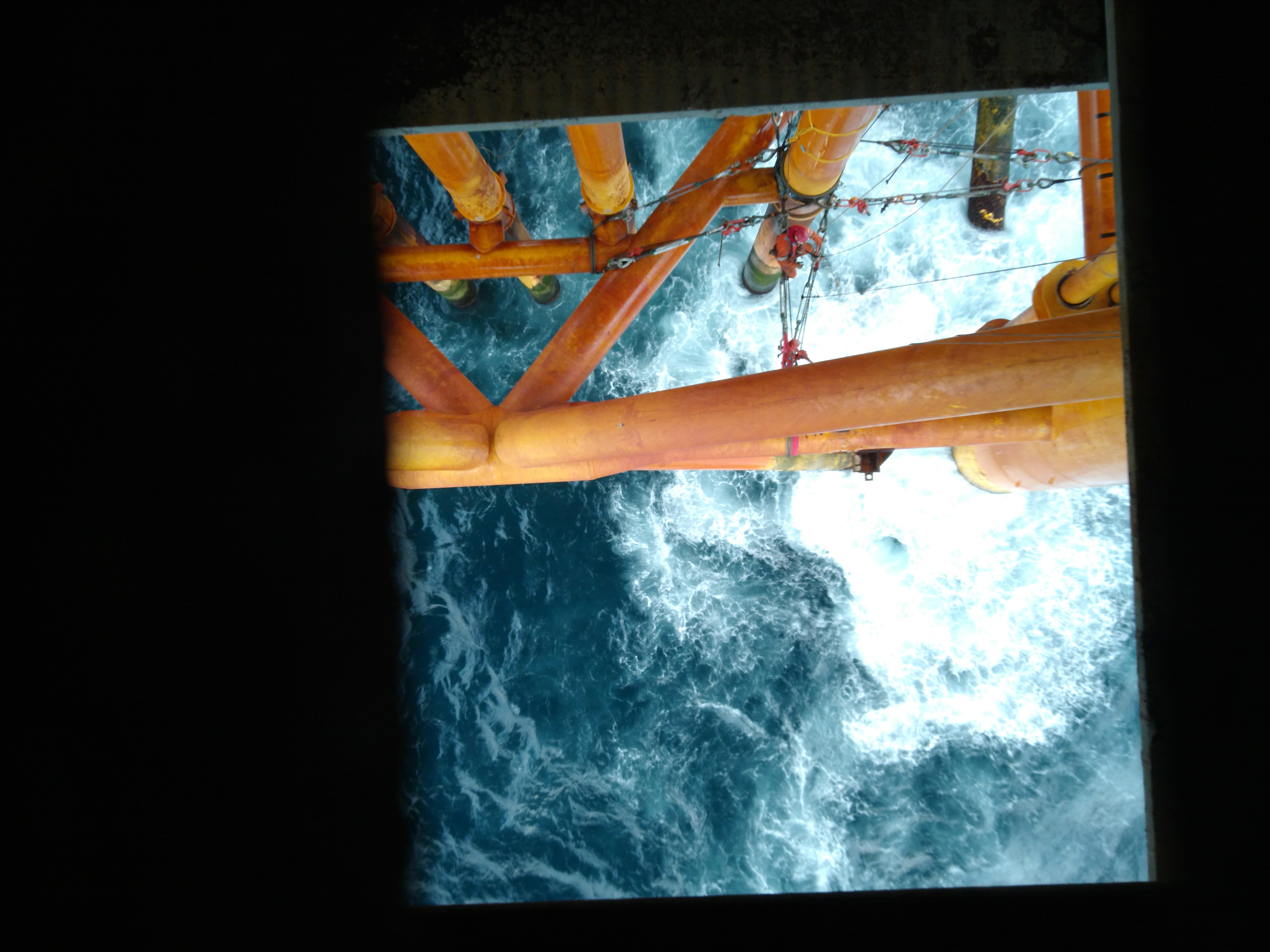 View down through offshore platform framing onto sea